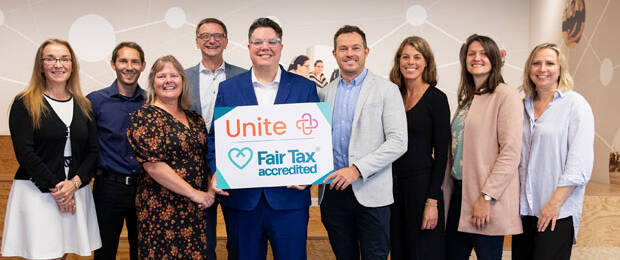 Graham Drummond (Mitte) übergibt die Fair-Tax-Mark-Akkreditierung an das Unite Team