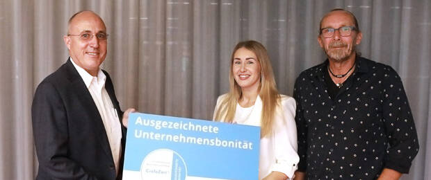 Karla Aßmann nimmt mit Dirk Aßmann (r.) für Assmann das CrefoZert von Armin Trojan (Creditreform) entgegen.